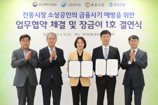 우리은행이이 5일 광장시장 인근 소재 종로4가금융센터에서 광장시장과 '장금이 1호 결연'을 맺었다. 김영재(왼쪽부터) 광장시장 상인총연합회 회장, 임종룡 우리금융그룹 회장, 이영 중소벤처기업부 장관, 이복현 금융감독원장, 정연기 우리은행 중소기업그룹 부행장이 기념촬영을 하고 있다. 우리금융그룹 제공